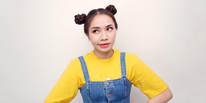 Young Asian Woman standing with hands on hips looking at camera posing in studio over white background