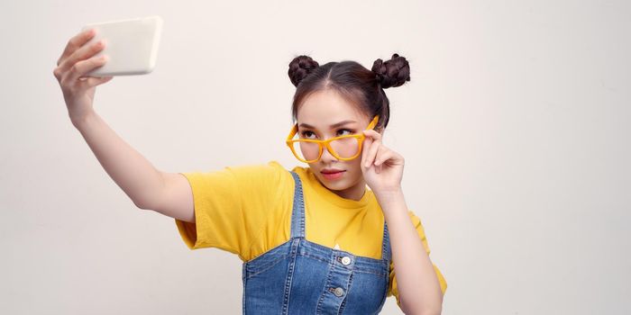 Photo of confident lady holding hands telephone making selfies wear specs yellow costume isolated white background