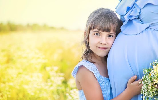 pregnant woman with daughter in a field of chamomile. Selective focus.