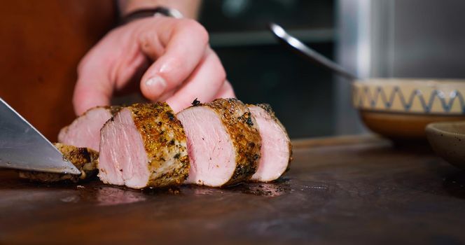 Chef Cuts Juicy Pork Steak on Rustic Cutting Board on Wooden Background. Concept of Delicious Meat Food. Close Up