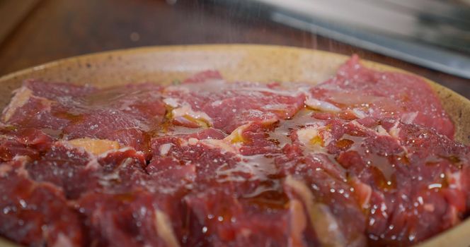 Seasoning raw beef meat on preparation table. cooking beef meat. Professional meat cooking.