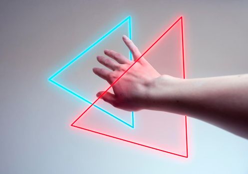 Hand entering in a neon light as a gate for new dimensions. Concept of new contemporary technology like metaverse, augmented reality and artificial intelligence.