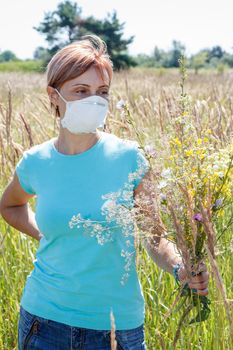 Woman in protective mask holding bouquet of wildflowers and trying to fight allergies to pollen. Natural daylight. Allergy concept.