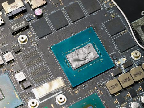 Graphics processor, GPU on the motherboard of a laptop computer, with thermal paste applied in the centre of the die. Cooling upgrade concept.