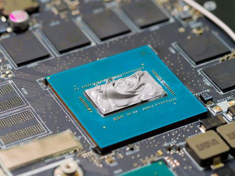 Graphics processor on the motherboard of a laptop computer, with thermal paste applied in the centre of the die. Cooling upgrade concept.