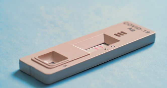Covid-19 Antigen Test - Sars COV 2 indicator on a blue background. The test result is positive, Two strips. Macro shooting.