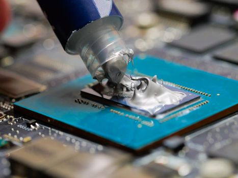 Technician applying thermal paste to a GPU on laptop motherboard. Thermal paste on the processor. Cleaning old thermal grease on the processor close-up.