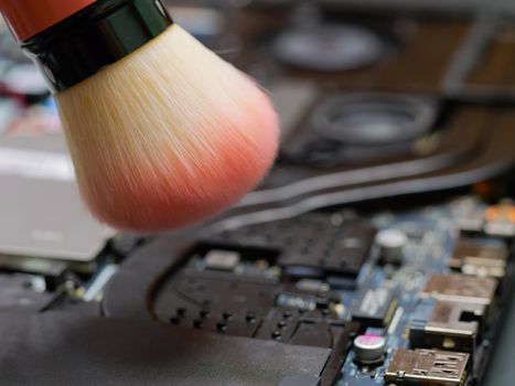 Cleaning the cooler system of laptop during maintenance or prophylaxis, removing the dust with brush. Repairs of electronic device concept.