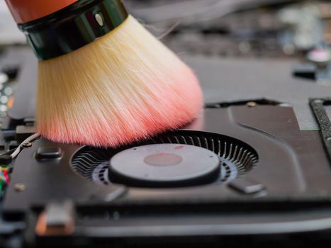 Macro of a brush cleaning a laptop fan at a professional service during maintenance or prophylaxis. Repairs of electronic device concept. Indoors.