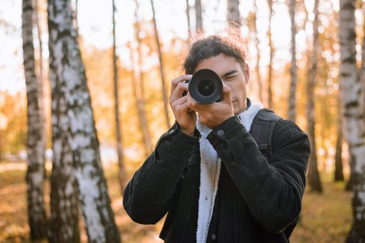 Portrait of a young male photographer shooting landscapes in the autumn forest
