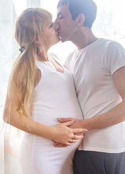 A pregnant woman and a father of a child hug a belly. Selective focus. NATURE.