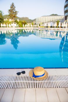 The concept of summer vacation - glasses, straw hat on the background of the hotel complex.