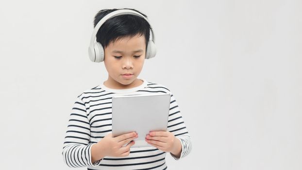 technology - a lovely young pupil standing with his tablet wearing headphones