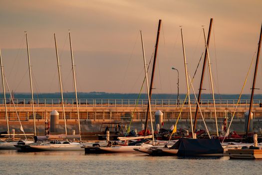 Russia, St. Petersburg, 10 June 2021: A few sailing yachts parked in a new port near the skyscraper of the gas company Gazprom at sunset, pontoons and piers, vintage wooden frigates in the background. High quality photo