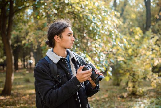 Photographer looking for good composition or interesting thing to shoot, standing in autumn forest