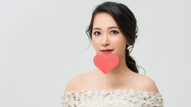 Portrait of pretty girl holding red paper heart on stick