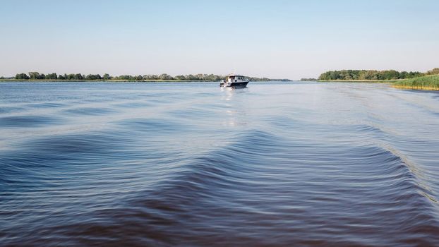 A large and wide rippling water and a small boat in the distance in the lagoon