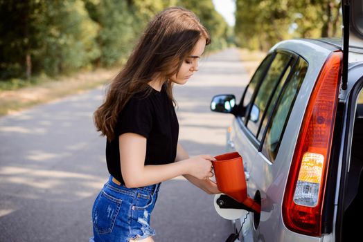 Attractive girl opens the lid of the fuel tank in the car and puts red bailer inside to fuel the tank