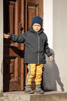 A little boy poses for a photographer on an autumn day at the ancient door in the center of Klaipeda's Old Town.