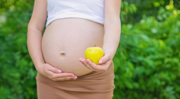 Pregnant woman with an apple in her hands. Selective focus. food.