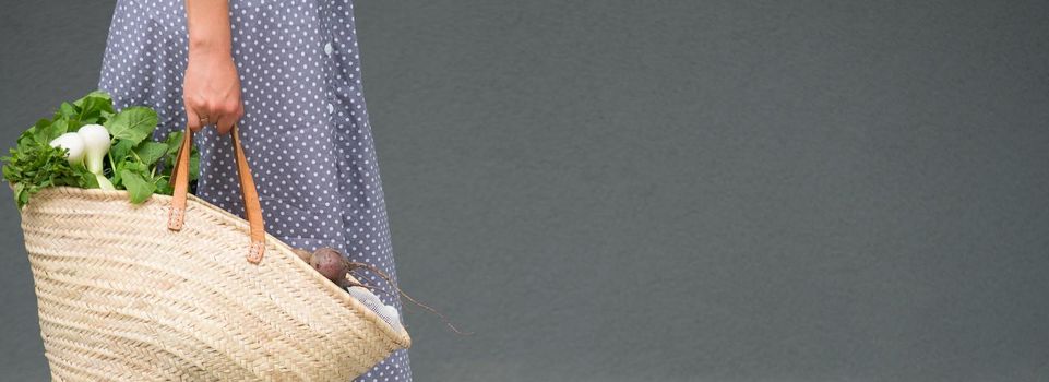 woman is holding straw back for shopping with products without plastic packaging. minimalistic concept