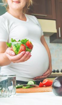 A pregnant woman eats vegetables and fruits. Selective focus. Food.