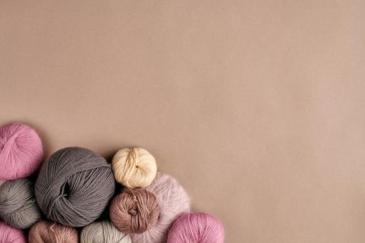 Set of colorful wool yarn on beige background. Knitting as a kind of needlework. Colorful balls of yarn and knitting needles. Top view. Still life. Copy space. Flat lay