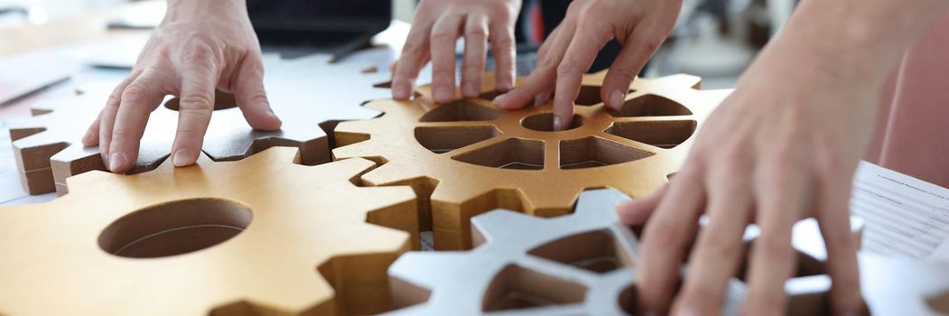 Business people stacking metal gears in office closeup. Brainstorming concept