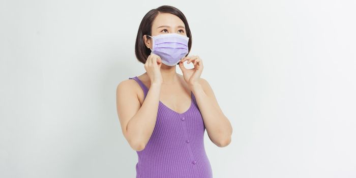 Pregnant woman in a protective mask against the flu and viruses on a white background. Health care concept