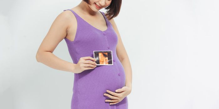 Pregnant girl shows an ultrasound photo of her undorn baby. Portrait of a child on an ultrasound phot