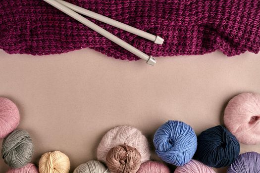 Set of colorful wool yarn on beige background. Knitting as a kind of needlework. Colorful balls of yarn and knitting needles. Top view. Still life. Copy space. Flat lay