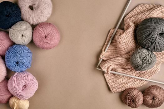 Set of colorful wool yarn and knitting on knitting needles on beige background. Knitting as a kind of needlework. Colorful balls of yarn and knitting needles. Top view. Still life. Copy space. Flat lay