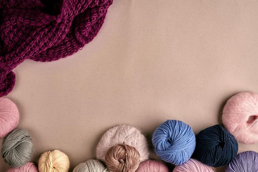 Set of colorful wool yarn on beige background. Knitting as a kind of needlework. Colorful balls of yarn and knitting needles. Top view. Still life. Copy space. Flat lay