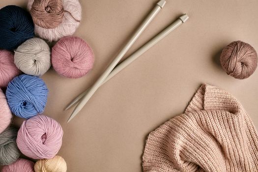 Set of colorful wool yarn and knitting on knitting needles on beige background. Knitting as a kind of needlework. Colorful balls of yarn and knitting needles. Top view. Still life. Copy space. Flat lay