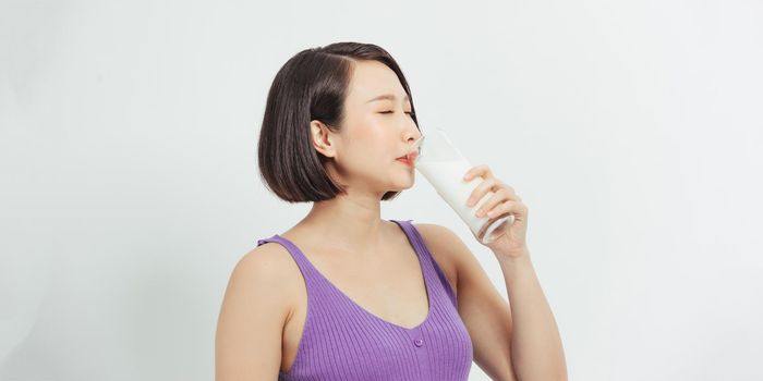 Pregnant woman with glass of milk showing thumb up copy space.