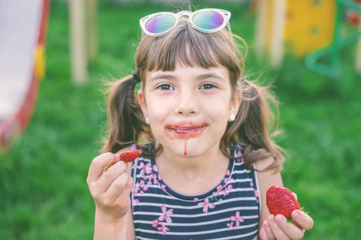 The child eats strawberries in the summer. Selective focus. people.