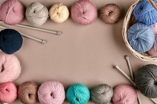 Set of colorful wool yarn on beige background. Knitting as a kind of needlework. Colorful balls of yarn and knitting needles. Top view. Still life. Copy space. Flat lay. Frame of tangles of knitting threads