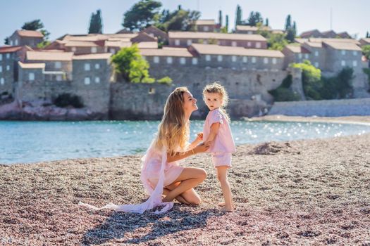 Mother and daughter tourists on background of beautiful view St. Stephen island, Sveti Stefan on the Budva Riviera, Budva, Montenegro. Travel to Montenegro concept.