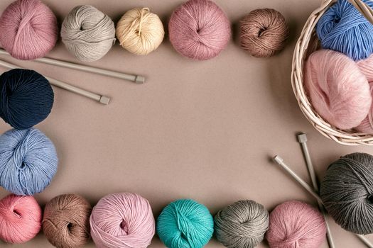 Set of colorful wool yarn on beige background. Knitting as a kind of needlework. Colorful balls of yarn and knitting needles. Top view. Still life. Copy space. Flat lay. Frame of tangles of knitting threads