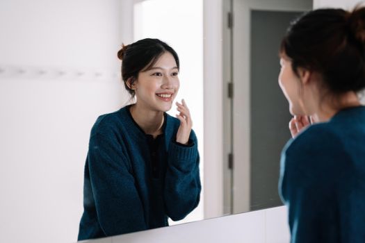 Portrait of beautiful asian woman looking at her face in mirror