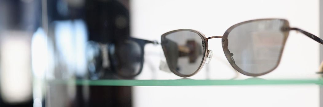 Stylish sunglasses lying on showcase in store closeup. Sale of fashion accessories concept