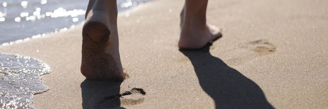 Barefoot female feet walking along sea beach closeup. Vacation at sea concept