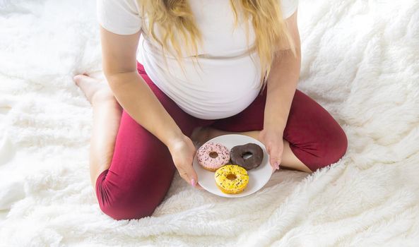 A pregnant woman eats sweet donuts. Selective Focus. Food.