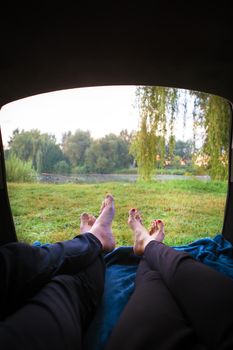 Man and woman relaxing in the trunk of a car near a lake.