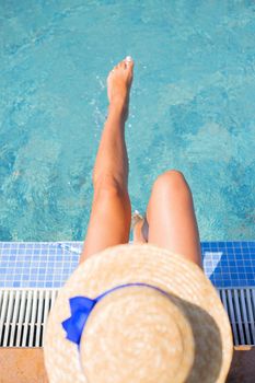Beautiful girl in a hat near a blue pool - sun, summer, heat. Top view.