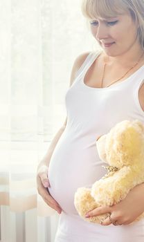 A pregnant woman with a toy hugs her stomach. Selective focus. People.
