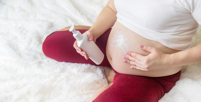 Pregnant woman smears cream from stretch marks. Selective Focus. people.