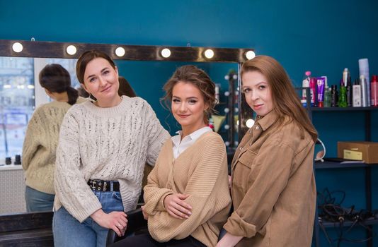Three beautiful girls are smiling while looking at the camera. A new look for a young woman. Business concept - beauty salon, facial skin and hair care.