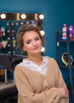 Girl with fashionable make-up and hairstyle smiling while looking at the camera. A new look for a young woman. Business concept - beauty salon, facial skin and hair care.