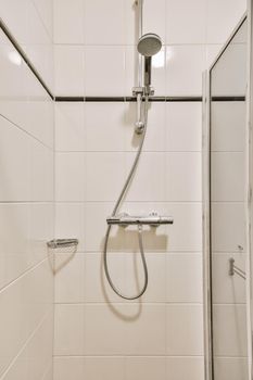 Bathtub with glass shower placed in corner near sink and toilet in small light bathroom with white tile walls